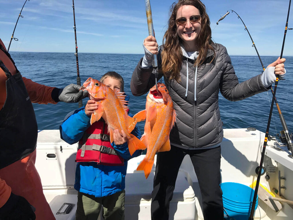 Mother and son anglers hold up canary rockfish while smiling.